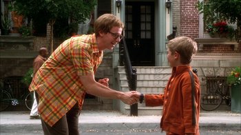 Movie still from “The Master of Disguise” (2002), directed by Perry Andelin Blake – A man and a boy shaking hands on the sidewalk; Medium shot, Over the shoulder angle