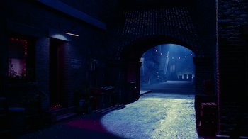Movie still from “The Master of Disguise” (2002), directed by Perry Andelin Blake – A dark alley way with a brick arch and lights on; Extreme Wide shot, High angle