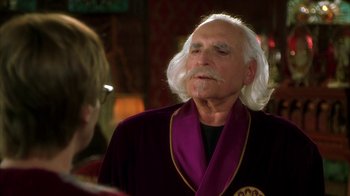 Movie still from “The Master of Disguise” (2002), directed by Perry Andelin Blake – An older man with long white hair wearing a purple robe; Close Up shot, Over the shoulder angle