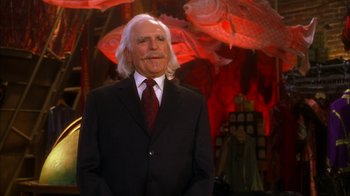 Movie still from “The Master of Disguise” (2002), directed by Perry Andelin Blake – A man in a suit and tie standing in front of a wall; Medium shot, Low angle