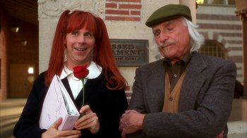 Movie still from “The Master of Disguise” (2002), directed by Perry Andelin Blake – A woman holding a red rose next to a man; Medium shot, High angle