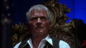 Movie still from “The Master of Disguise” (2002), directed by Perry Andelin Blake – An older man with a mustache sitting in a chair; Close Up shot, Low angle