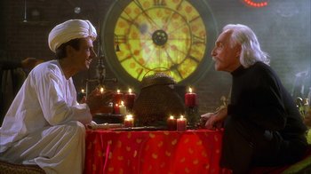 Movie still from “The Master of Disguise” (2002), directed by Perry Andelin Blake – Two men sitting at a table with candles; Medium shot, Over the shoulder angle