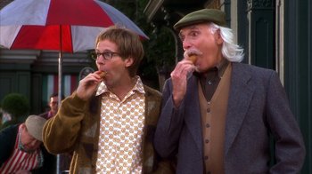 Movie still from “The Master of Disguise” (2002), directed by Perry Andelin Blake – Two men are standing outside eating some food; Medium shot, Low angle