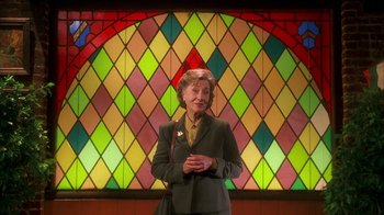 Movie still from “The Master of Disguise” (2002), directed by Perry Andelin Blake – An older woman standing in front of a stained glass window; Medium shot, Low angle