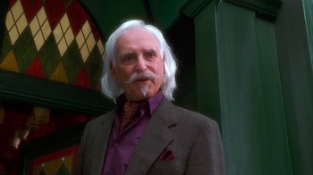 Movie still from “The Master of Disguise” (2002), directed by Perry Andelin Blake – An older man with long white hair wearing a suit and tie; Close Up shot, Low angle