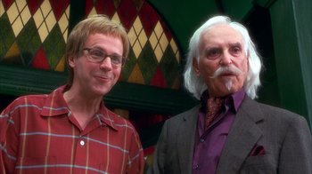 Movie still from “The Master of Disguise” (2002), directed by Perry Andelin Blake – Two men standing next to each other in front of a wall; Medium shot, Low angle