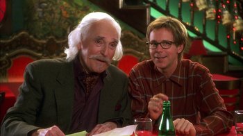 Movie still from “The Master of Disguise” (2002), directed by Perry Andelin Blake – Two men sitting at a table with a bottle of beer; Medium shot, Over the shoulder angle
