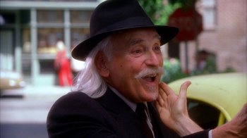 Movie still from “The Master of Disguise” (2002), directed by Perry Andelin Blake – An older man with a long white beard wearing a black suit and a black hat; Close Up shot, Over the shoulder angle