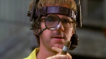 Movie still from “The Master of Disguise” (2002), directed by Perry Andelin Blake – A man wearing a headset and holding a cell phone in his hand; Close Up shot, Low angle