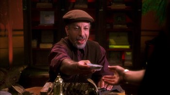 Movie still from “The Master of Disguise” (2002), directed by Perry Andelin Blake – An older man in a hat is handing a card to someone else; Close Up shot, Over the shoulder angle