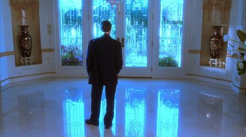 Movie still from “The Master of Disguise” (2002), directed by Perry Andelin Blake – A man standing in front of a large glass door; Wide shot, Low angle