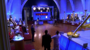 Movie still from “The Master of Disguise” (2002), directed by Perry Andelin Blake – Three men are standing in front of a stage in a ballroom; Extreme Wide shot, High angle