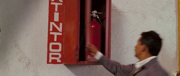 Movie still from “The Matador” (2005), directed by Richard Shepard – A man in a business suit is opening a fire hydrant; Close Up shot, High angle