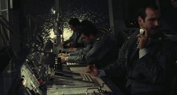 Movie still from “The Mattei Affair” (1972), directed by Francesco Rosi – A group of men working on laptops in a dark room; Medium shot, Low angle