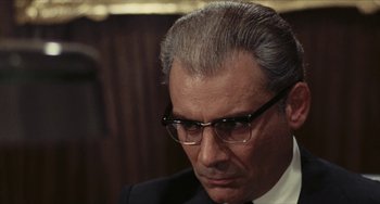 Movie still from “The Mattei Affair” (1972), directed by Francesco Rosi – An older man wearing glasses and a suit; Close Up shot, Over the shoulder angle