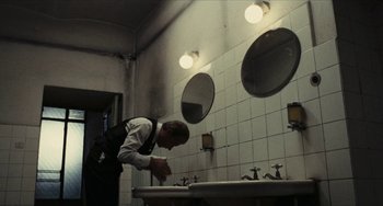 Movie still from “The Mattei Affair” (1972), directed by Francesco Rosi – A man in a bathroom looking at a sink; Medium shot, Low angle