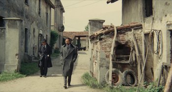 Movie still from “The Mattei Affair” (1972), directed by Francesco Rosi – Two men walking down a street in a city; Wide shot, Low angle