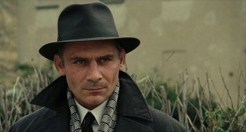 Movie still from “The Mattei Affair” (1972), directed by Francesco Rosi – A man wearing a hat and a coat; Close Up shot, Over the shoulder angle