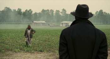 Movie still from “The Mattei Affair” (1972), directed by Francesco Rosi – Two men are standing in the middle of an open field; Wide shot, Over the shoulder angle