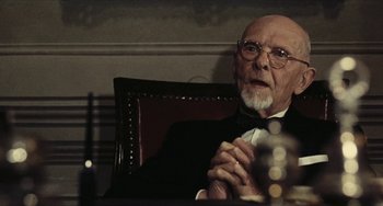 Movie still from “The Mattei Affair” (1972), directed by Francesco Rosi – An older man sitting in a chair with his hands clasped together; Close Up shot, Low angle