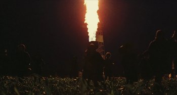 Movie still from “The Mattei Affair” (1972), directed by Francesco Rosi – People standing in a field near a gas flare at night; Extreme Wide shot, Low angle