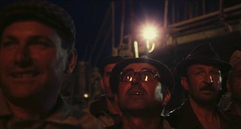Movie still from “The Mattei Affair” (1972), directed by Francesco Rosi – A group of men standing next to each other at night; Close Up shot, Low angle