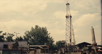 Movie still from “The Mattei Affair” (1972), directed by Francesco Rosi – An oil rig sits in the middle of a field; Extreme Wide shot, Low angle