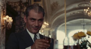 Movie still from “The Mattei Affair” (1972), directed by Francesco Rosi – A man in a suit holding a glass of wine; Close Up shot, Low angle