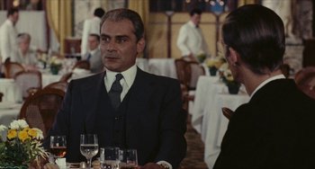 Movie still from “The Mattei Affair” (1972), directed by Francesco Rosi – A man and woman sitting at a dinner table; Medium shot, Over the shoulder angle