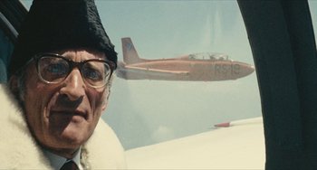 Movie still from “The Mattei Affair” (1972), directed by Francesco Rosi – An older man wearing a hat and glasses looking out a window at an airplane; Close Up shot, Low angle