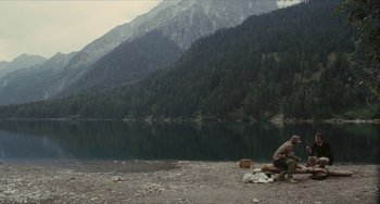 Movie still from “The Mattei Affair” (1972), directed by Francesco Rosi – A man sitting on the ground next to a body of water; Extreme Wide shot, High angle