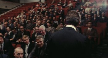 Movie still from “The Mattei Affair” (1972), directed by Francesco Rosi – A crowd of people sitting in front of an audience; Wide shot, Over the shoulder angle