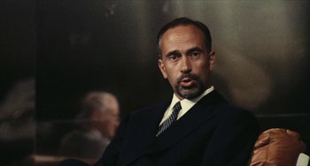 Movie still from “The Mattei Affair” (1972), directed by Francesco Rosi – A person wearing a suit and tie; Close Up shot, Low angle