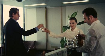 Movie still from “The Mattei Affair” (1972), directed by Francesco Rosi – A woman is handing a glass to a man; Medium shot, Low angle