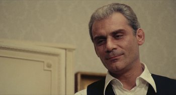 Movie still from “The Mattei Affair” (1972), directed by Francesco Rosi – A person wearing a suit and tie; Close Up shot, Over the shoulder angle