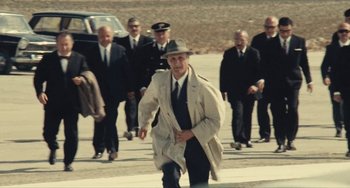 Movie still from “The Mattei Affair” (1972), directed by Francesco Rosi – An older man in a trench coat and a hat walking down the street; Wide shot, High angle