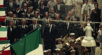 Movie still from “The Mattei Affair” (1972), directed by Francesco Rosi – A group of men in suits standing next to each other in front of a flag; Extreme Wide shot, High angle