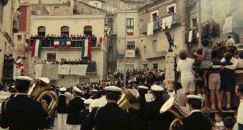 Movie still from “The Mattei Affair” (1972), directed by Francesco Rosi – A group of people in uniforms marching down a street; Extreme Wide shot, High angle