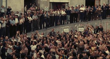 Movie still from “The Mattei Affair” (1972), directed by Francesco Rosi – A crowd of people standing on steps in front of a building; Extreme Wide shot, High angle