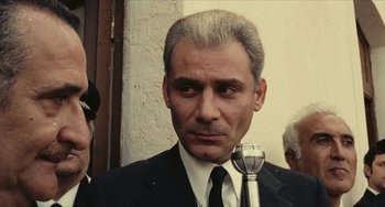 Movie still from “The Mattei Affair” (1972), directed by Francesco Rosi – A person holding a microphone; Close Up shot, Low angle