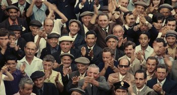 Movie still from “The Mattei Affair” (1972), directed by Francesco Rosi – A group of men in suits and hats clapping; Wide shot, High angle