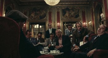 Movie still from “The Mattei Affair” (1972), directed by Francesco Rosi – A group of men sitting around a table drinking coffee; Wide shot, Over the shoulder angle