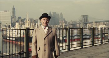 Movie still from “The Mattei Affair” (1972), directed by Francesco Rosi – An older man in a hat and coat standing in front of a fence; Medium shot, Low angle