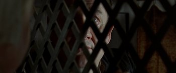 Movie still from “The Messenger: The Story of Joan of Arc” (1999), directed by Luc Besson – A person behind a metal fence; Close Up shot, Overhead angle