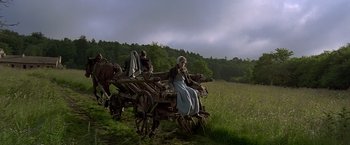 Movie still from “The Messenger: The Story of Joan of Arc” (1999), directed by Luc Besson – A woman sitting on a horse drawn carriage in the middle of a field; Wide shot, Low angle