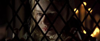 Movie still from “The Messenger: The Story of Joan of Arc” (1999), directed by Luc Besson – A young girl looking through a chain link fence; Close Up shot, High angle
