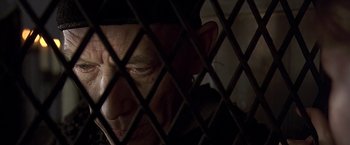 Movie still from “The Messenger: The Story of Joan of Arc” (1999), directed by Luc Besson – An older man looking through a fence; Close Up shot, Low angle