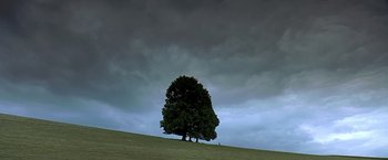 Movie still from “The Messenger: The Story of Joan of Arc” (1999), directed by Luc Besson – A tree on a grassy hill under a cloudy sky; Extreme Wide shot, Low angle