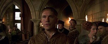 Movie still from “The Messenger: The Story of Joan of Arc” (1999), directed by Luc Besson – A group of men standing next to each other in a room; Close Up shot, Over the shoulder angle